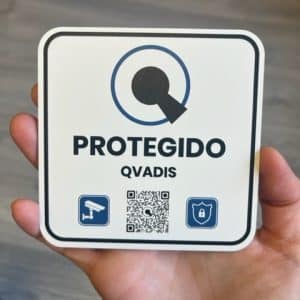 Placa disuasoria Protegido Qvadis sujeta en la palma de una mano.